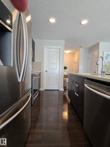 Kitchen featuring wood-finish flooring, stainless steel appliances, dark cabinetry, light countertops, and recessed lighting - 491 Ebbers Way, Edmonton, AB 