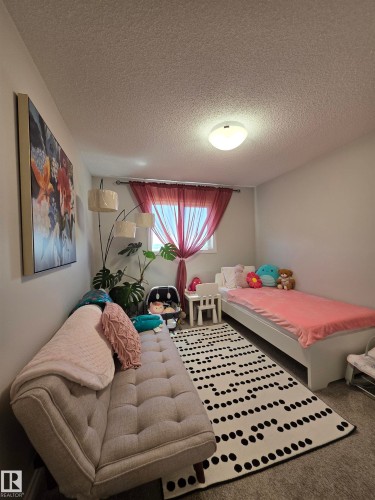 Room featuring neutral wall paint, a window with red sheer curtains, and a flush-mount ceiling light fixture - 491 Ebbers Way, Edmonton, AB 