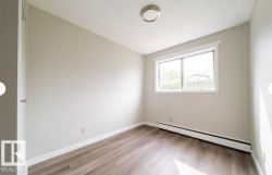 Room featuring wood-finish flooring, a contemporary flush-mount ceiling light, white baseboards, and a large window with white trim - 