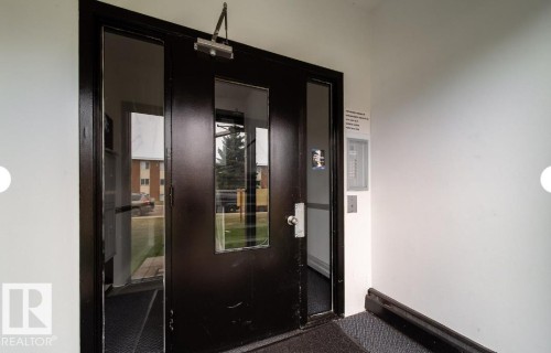 Black entry door with multiple glass inserts, framed by a dark trim and adjacent fixed side panels - 3415 106 Avenue Northwest, Edmonton, AB - Indoor Photo Showing Other Room