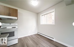 Kitchen area featuring wood-finish upper cabinetry, a built-in range hood, and a white electric range - 