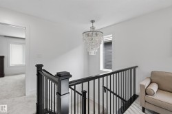 Staircase featuring dark wood newel posts and handrail, black metal balusters, and a tiered crystal chandelier - 