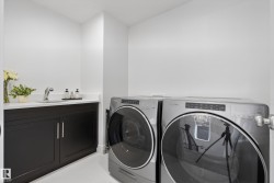 Laundry area featuring a built-in sink with a countertop, dark wood-finish cabinetry, and white walls - 