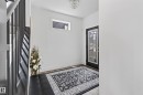 Entryway featuring a black-framed door with decorative glass, wood-finish flooring, a contemporary ceiling light fixture, and a transom window - 61 Encore Crescent, St. Albert, AB  - Indoor Photo Showing Other Room 