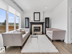 Living area featuring a stone-faced fireplace with a dark wood mantel, recessed lighting, and wood-finish flooring - 
