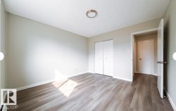 Room featuring wood-finish flooring, light neutral wall paint, and white baseboards - 