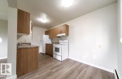 Kitchen featuring wood-finish cabinetry, stone-look countertops, and white appliances - 