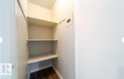 Utility closet with built-in shelving, wood-finish flooring, and electrical panel access - 