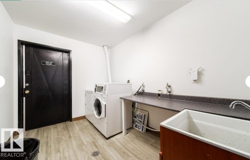Dedicated laundry area featuring wood-finish flooring and a utility sink - 3415 106 Avenue Northwest, Edmonton, AB - Indoor Photo Showing Laundry Room