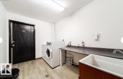 Dedicated laundry area featuring wood-finish flooring and a utility sink - 