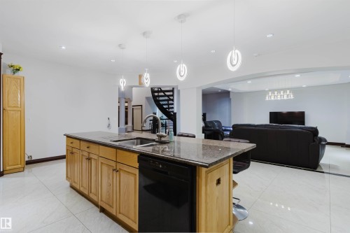 Kitchen island featuring light wood-finish cabinetry, granite countertop, and integrated stainless steel sink - 4103 Westcliff Heath Heath Sw, Edmonton, AB - Indoor Photo Showing Kitchen With Double Sink