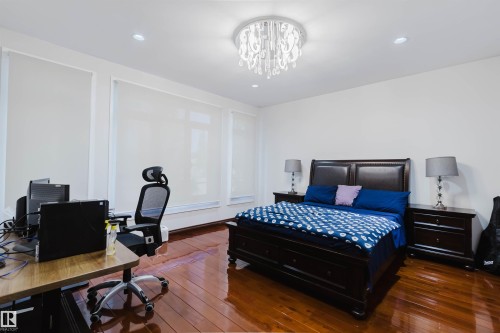 Spacious room featuring rich wood-finish flooring, recessed lighting, and a modern ceiling light fixture - 4103 Westcliff Heath Heath Sw, Edmonton, AB - Indoor Photo Showing Bedroom