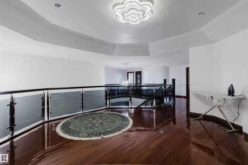 Expansive upper-level landing featuring polished wood-finish flooring and a contemporary glass and metal railing system - 4103 Westcliff Heath Heath Sw, Edmonton, AB - Indoor