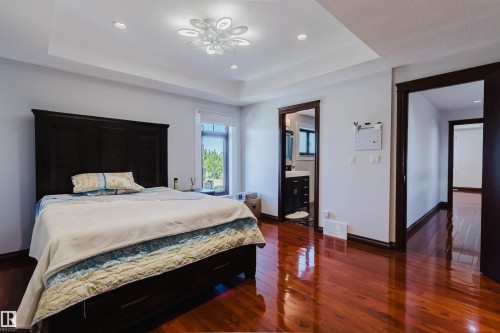 Bedroom featuring rich wood-finish flooring, a tray ceiling with recessed lighting, and a contemporary ceiling fixture - 4103 Westcliff Heath Heath Sw, Edmonton, AB - Indoor Photo Showing Bedroom