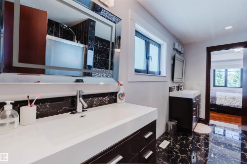 Dual vanity bathroom featuring black marble-style flooring, a large framed mirror, and a window for natural light - 4103 Westcliff Heath Heath Sw, Edmonton, AB - Indoor Photo Showing Bathroom