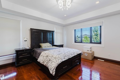 Spacious room featuring rich wood-finish flooring, a tray ceiling with recessed lighting, and a decorative ceiling fixture - 4103 Westcliff Heath Heath Sw, Edmonton, AB - Indoor Photo Showing Bedroom