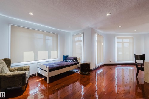 Spacious room featuring polished wood-finish flooring, recessed lighting, multiple windows with roller shades, and crisp white walls - 4103 Westcliff Heath Heath Sw, Edmonton, AB - Indoor