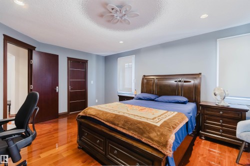 Spacious bedroom featuring gleaming wood-finish flooring, light gray wall paint, and two dark wood doors - 4103 Westcliff Heath Heath Sw, Edmonton, AB - Indoor Photo Showing Bedroom