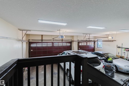 Spacious garage featuring two sectional garage doors with automatic openers, overhead fluorescent lighting, and a single window - 4103 Westcliff Heath Heath Sw, Edmonton, AB - Indoor Photo Showing Garage