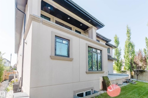 Exterior stucco finish, decorative window trim, modern dark-framed windows, dark soffit with recessed lighting, and a manicured lawn - 4103 Westcliff Heath Heath Sw, Edmonton, AB - Outdoor With Exterior