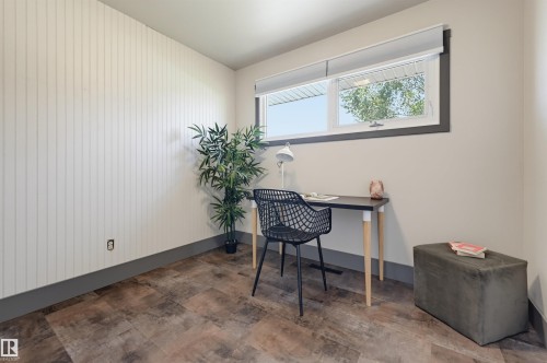 Room with wood-finish flooring, a white vertical paneled accent wall, a window with a dark trim, and light-toned walls - 8716 130 Avenue Nw, Edmonton, AB - Indoor