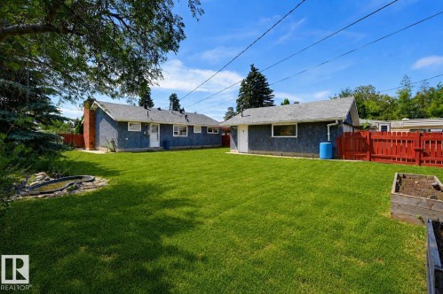 Expansive green lawn with a red privacy fence and mature trees - 8716 130 Avenue Nw, Edmonton, AB - Outdoor
