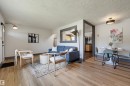 Open-concept living area featuring wood-finish flooring, white walls with dark trim accents, and a built-in pass-through window - 8716 130 Avenue Nw, Edmonton, AB  - Indoor 
