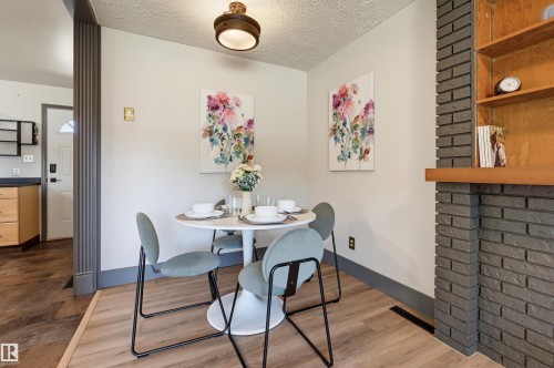 Dining area featuring light wood-finish flooring, a contemporary ceiling light fixture, a dark brick fireplace surround, and built-in wood shelving - 8716 130 Avenue Nw, Edmonton, AB - Indoor Photo Showing Dining Room