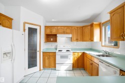 Kitchen featuring wood cabinetry, white tile backsplash, light blue countertops, and white appliances - 