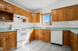 U-shaped kitchen featuring wood cabinetry with gold-toned hardware, white tile backsplash, and light green countertops - 