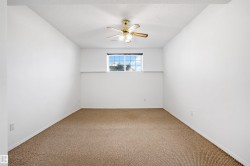 Room featuring light brown carpeting, white painted walls, a window with gridded panes, and a ceiling fan with integrated lighting - 