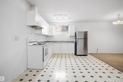 Kitchen featuring white cabinetry, a built-in range hood, white range, stainless steel refrigerator, and patterned floor tiles - 