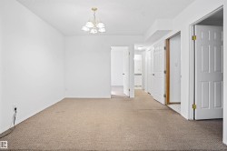 Carpeted interior room with white walls and a multi-light chandelier - 