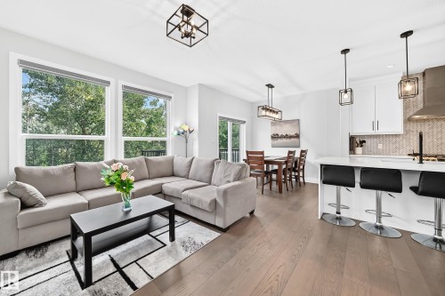 Open-concept living space featuring wood-finish flooring, white walls, and a modern kitchen - 22270 99A Avenue Nw, Edmonton, AB - Indoor Photo Showing Living Room