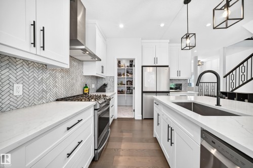 Modern kitchen featuring white cabinetry, light-toned countertops, and a herringbone tile backsplash - 22270 99A Avenue Nw, Edmonton, AB - Indoor Photo Showing Kitchen With Stainless Steel Kitchen With Upgraded Kitchen
