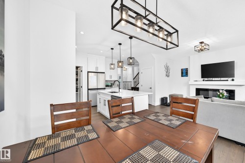 Open-concept living area featuring a formal dining space, kitchen island, and contemporary fireplace - 22270 99A Avenue Nw, Edmonton, AB - Indoor Photo Showing Other Room