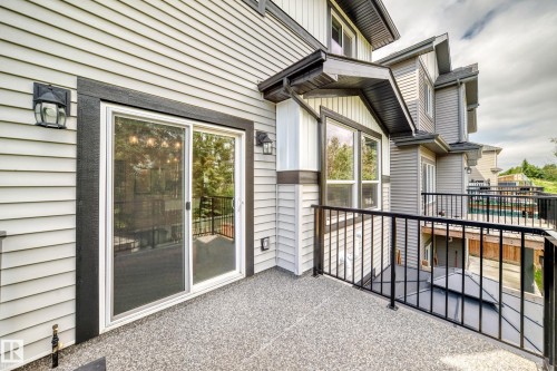 Private outdoor deck featuring a textured aggregate surface, black metal railings, and a sliding glass door entry - 22270 99A Avenue Nw, Edmonton, AB - Outdoor With Exterior