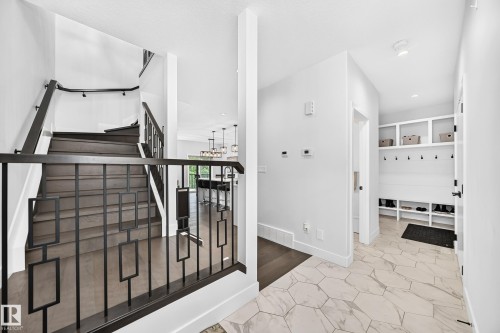 Hexagonal tile flooring, built-in mudroom storage, wood-finish flooring staircase, and contemporary black metal railings - 22270 99A Avenue Nw, Edmonton, AB - Indoor Photo Showing Other Room
