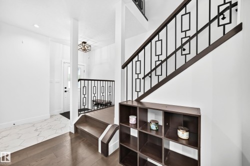 Contemporary staircase featuring dark wood-finish handrails and decorative black metal balusters - 22270 99A Avenue Nw, Edmonton, AB - Indoor Photo Showing Other Room