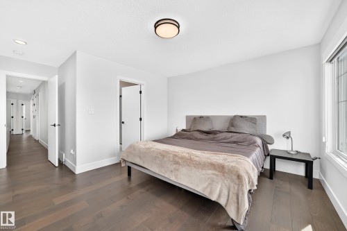 Bedroom featuring dark wood-finish flooring, white walls, a large window, and a modern flush-mount ceiling light - 22270 99A Avenue Nw, Edmonton, AB - Indoor Photo Showing Bedroom