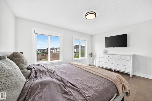 Bright room with two large windows, dark wood-finish flooring, a flush-mount ceiling light fixture, and white painted walls - 22270 99A Avenue Nw, Edmonton, AB - Indoor Photo Showing Bedroom