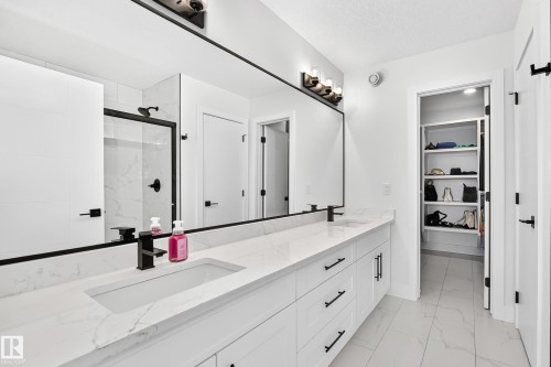 Contemporary bathroom featuring a large double vanity with integrated sinks, white cabinetry, and a full-width mirror - 22270 99A Avenue Nw, Edmonton, AB - Indoor