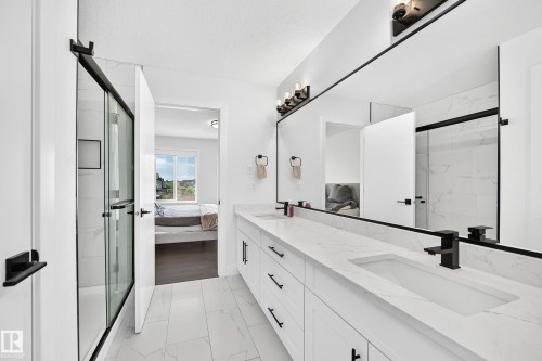Spacious bathroom featuring a double vanity with integrated sinks, white countertops, and matte black fixtures - 22270 99A Avenue Nw, Edmonton, AB - Indoor