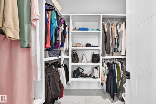 Integrated custom closet system featuring white shelving, multiple hanging rods, and open storage compartments - 22270 99A Avenue Nw, Edmonton, AB - Indoor With Storage