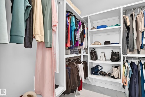 Integrated closet system featuring white shelving and chrome hanging rods - 22270 99A Avenue Nw, Edmonton, AB - Indoor With Storage