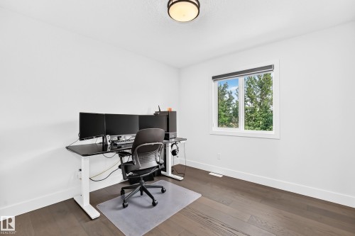 Bright room featuring a prominent window, dark wood-finish flooring, white walls, white baseboards, and a flush-mount ceiling light fixture - 22270 99A Avenue Nw, Edmonton, AB - Indoor Photo Showing Office