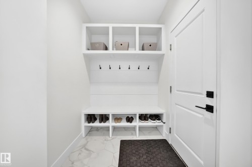 Built-in storage bench with overhead cubbies and wall hooks, set against white shiplap paneling - 22270 99A Avenue Nw, Edmonton, AB - Indoor Photo Showing Laundry Room