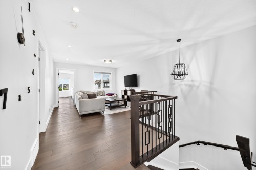 Open-concept living space featuring wood-finish flooring, recessed lighting, and a contemporary geometric pendant light - 22270 99A Avenue Nw, Edmonton, AB - Indoor