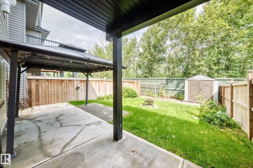 Concrete patio area with a covered gazebo, grass lawn, wood fencing, and a storage shed - 22270 99A Avenue Nw, Edmonton, AB - Outdoor
