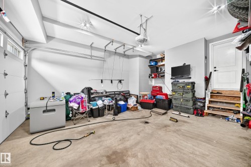 Spacious garage featuring a paneled overhead door, concrete flooring, recessed lighting, built-in shelving, and a service door - 22270 99A Avenue Nw, Edmonton, AB - Indoor Photo Showing Garage